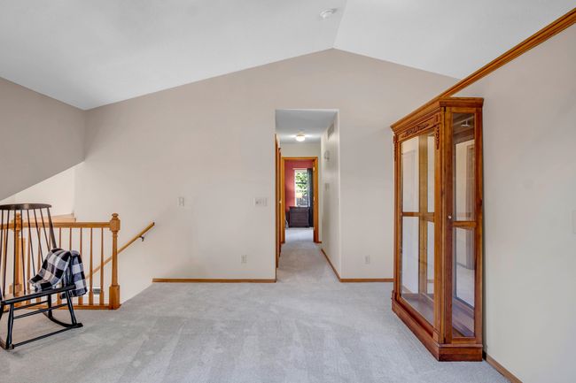 Corridor featuring an upstairs landing, vaulted ceiling, carpet floors, and baseboards | Image 6