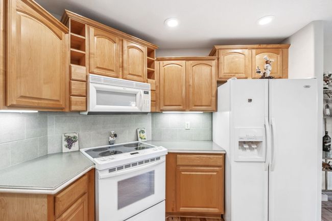 Kitchen with white appliances, open shelves, light countertops, and backsplash | Image 8