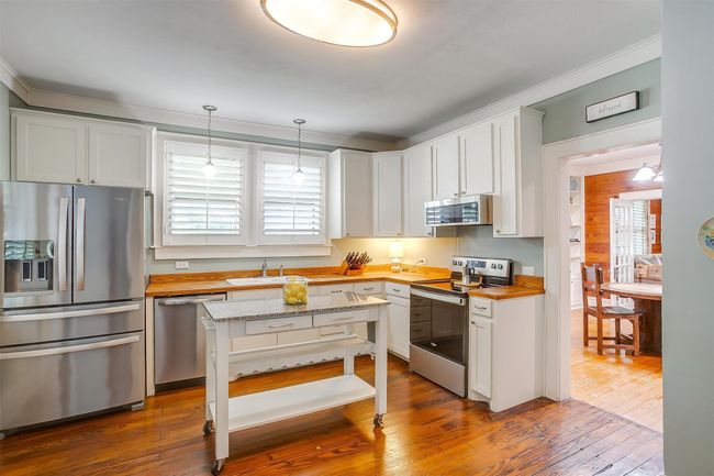 Kitchen with appliances with stainless steel finishes, ornamental molding, dark wood-style flooring, wood counters, and hanging light fixtures | Image 30