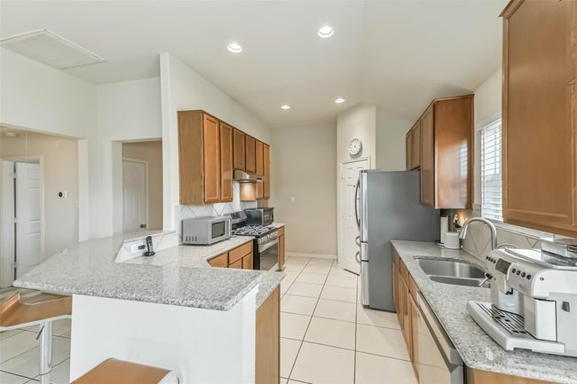 Elegant granite countertops adorn the kitchen and breakfast bar. | Image 10