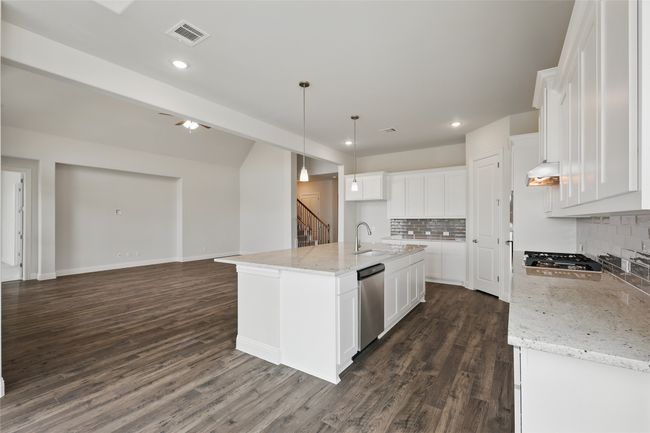 Kitchen with dark wood finished floors, open floor plan, white cabinets, and stainless steel appliances | Image 4