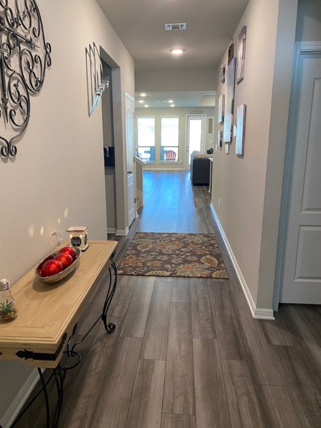 Hallway featuring visible vents, baseboards, and wood finished floors | Image 8