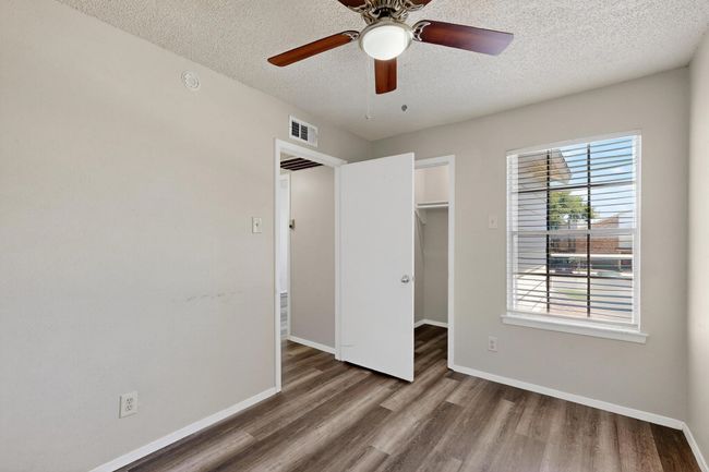 Unfurnished bedroom with a textured ceiling, a spacious closet, wood finished floors, and a ceiling fan | Image 24