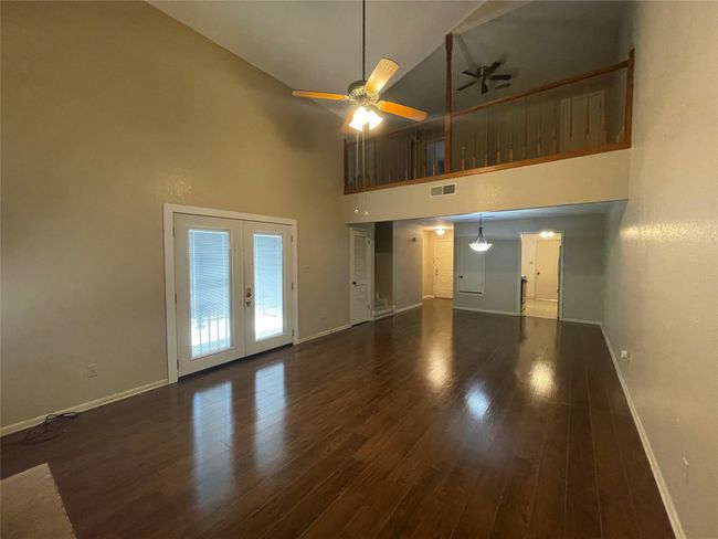 Unfurnished living room featuring baseboards, a high ceiling, ceiling fan, french doors, and wood finished floors | Image 12