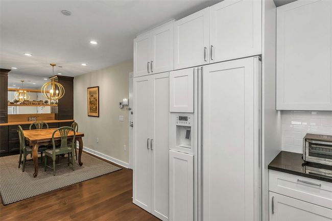 Kitchen with dark wood-type flooring, backsplash, recessed lighting, a chandelier, and white cabinetry | Image 7