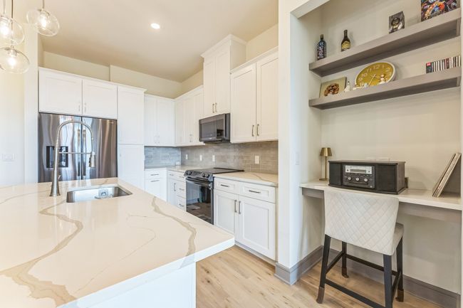 Kitchen with light wood-style floors, stainless steel appliances, white cabinetry, and light stone countertops | Image 11