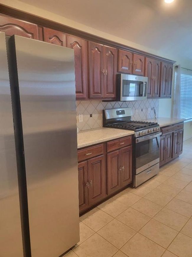 One side of the kitchen showing the refrigerator. | Image 7