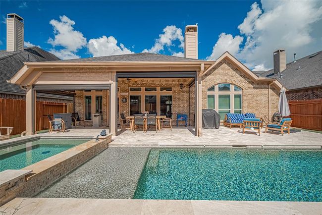 The expansive travertine decking around the pool creates multiple sitting areas, perfect for lounging, entertaining, or soaking up the sun. | Image 31