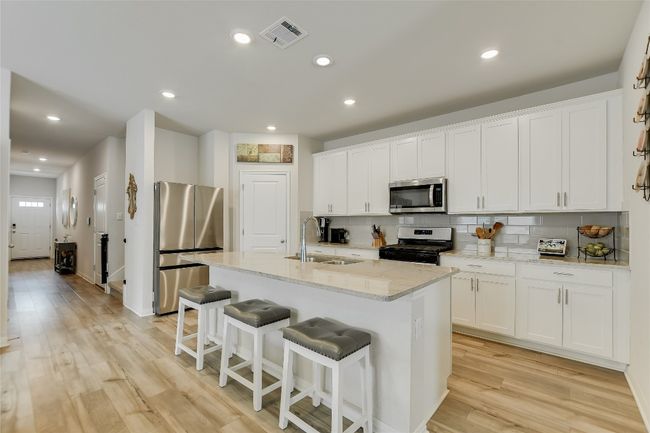 Kitchen featuring stainless steel appliances, a sink, a center island with sink, a breakfast bar area, and light wood-style floors | Image 8