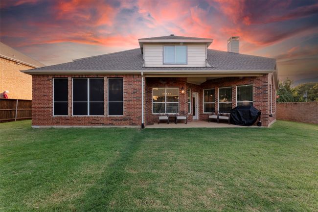 Back of house at dusk with a chimney, brick siding, and a fenced backyard | Image 35