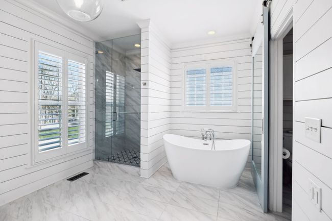 Freestanding soaking tub, large walk-in shower, and shiplap walls offer a luxurious retreat. | Image 18