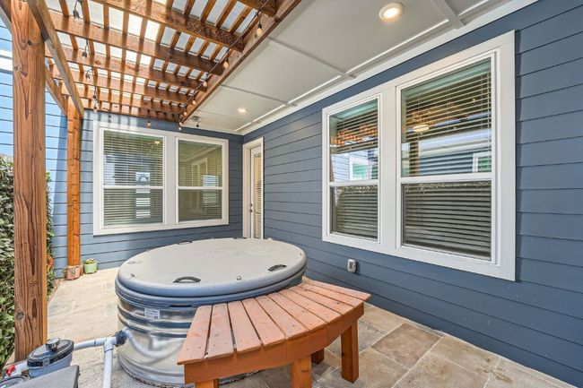 View of patio featuring an outdoor hot tub and a pergola With custom bench. | Image 26