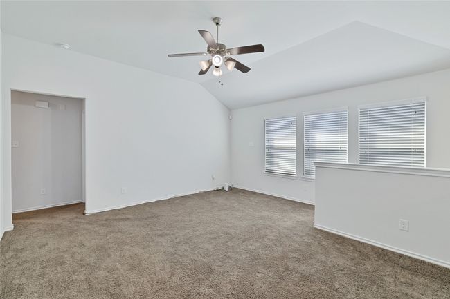 Carpeted empty room featuring vaulted ceiling, a ceiling fan, and a smoke detector | Image 21