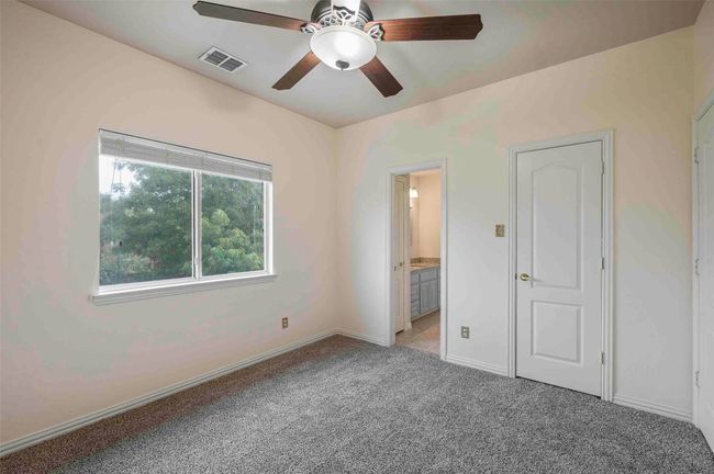 Unfurnished bedroom featuring connected bathroom, a ceiling fan, visible vents, light carpet, and baseboards | Image 19