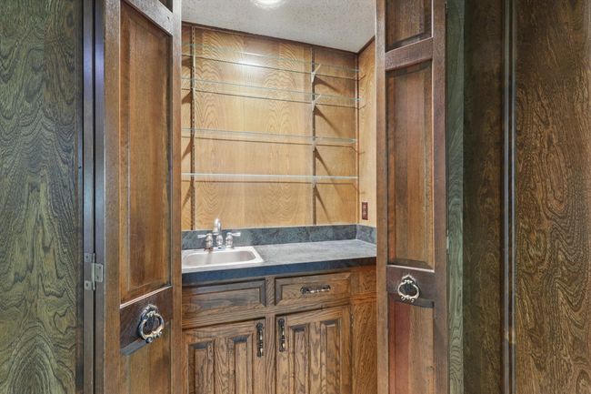 Bathroom featuring wooden walls, vanity, and a textured ceiling | Image 17
