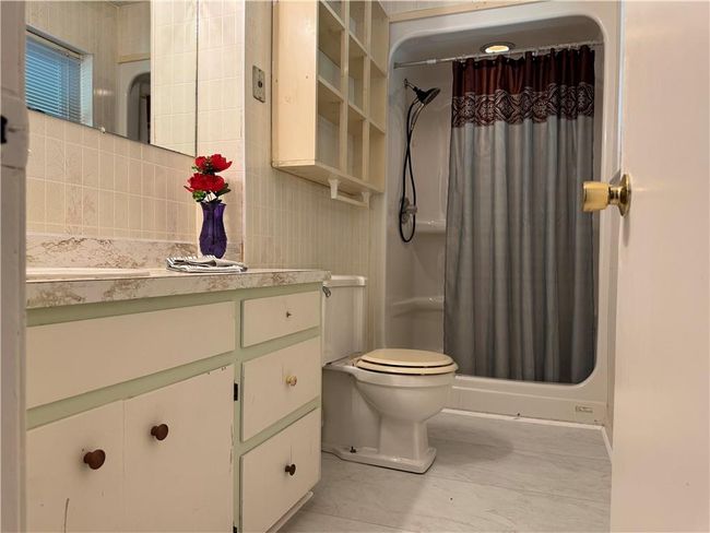 Bathroom featuring vanity, curtained shower, marble finish flooring, and backsplash | Image 12
