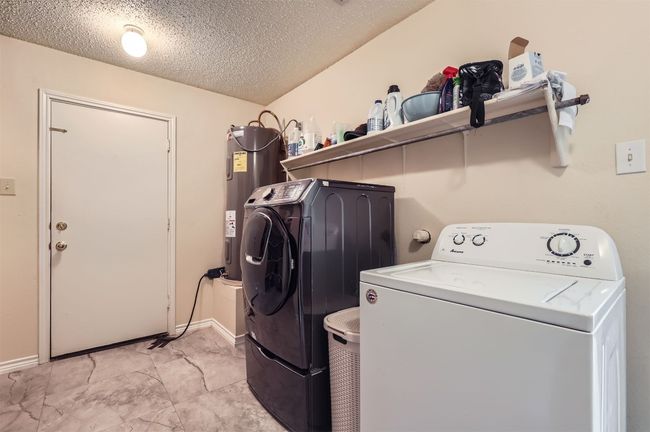 Laundry room featuring separate washer and dryer, water heater, a textured ceiling, and baseboards | Image 25