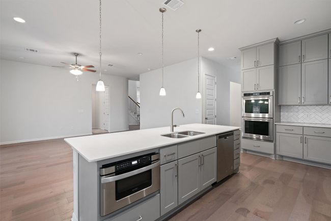 Kitchen with a sink, tasteful backsplash, gray cabinetry, stainless steel appliances, and visible vents | Image 13