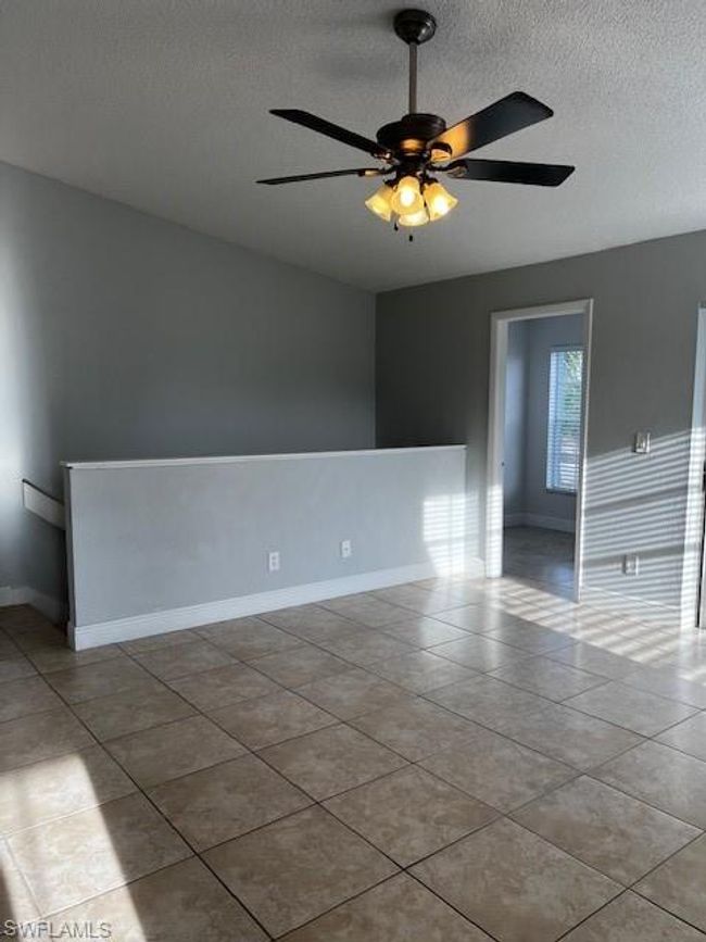 Spare room with tile patterned floors, baseboards, ceiling fan, and a textured ceiling | Image 4