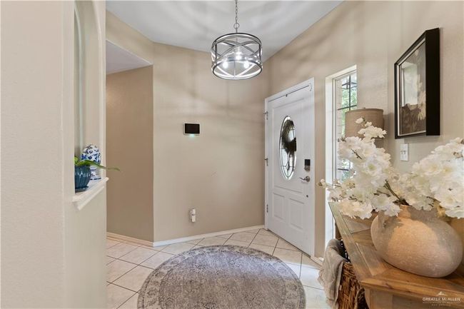 Entrance foyer featuring light tile patterned flooring, a chandelier, and baseboards | Image 7