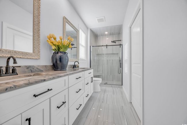 Bathroom featuring a stall shower, double vanity, and toilet | Image 14