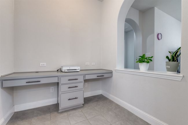 Unfurnished office with light tile patterned floors, arched walkways, built in study area, and baseboards | Image 14