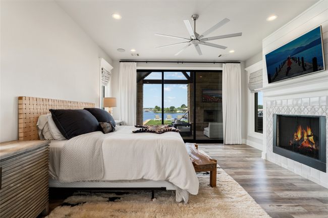 Bedroom with a tiled fireplace, access to outside, wood finished floors, and recessed lighting | Image 11