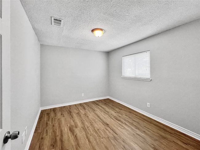 Empty room with wood finished floors and a textured ceiling | Image 15