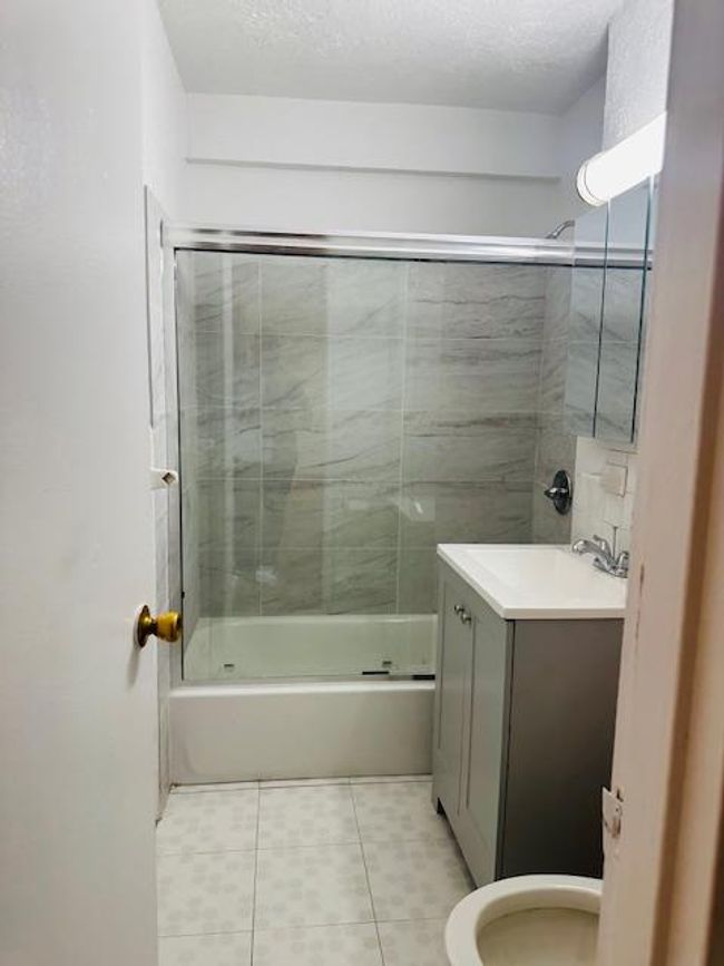 Bathroom featuring tile patterned flooring, vanity, and enclosed tub / shower combo | Image 13