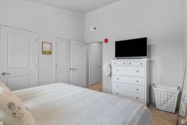Bedroom with lofted ceiling, visible vents, and carpet | Image 24