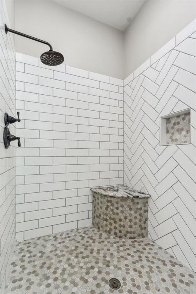Indulge in the spacious walk-in shower, complete with dual shower heads, a handy corner bench, and a recessed shampoo niche. | Image 21