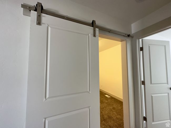 Hallway featuring carpet and a barn door into bonus/game room | Image 10