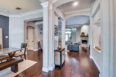 Hallway with crown molding, dark wood-type flooring, and decorative columns | Image 2