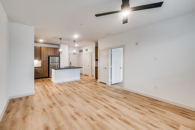 Unfurnished living room featuring light wood-style flooring, a ceiling fan, baseboards, and a sink | Image 9