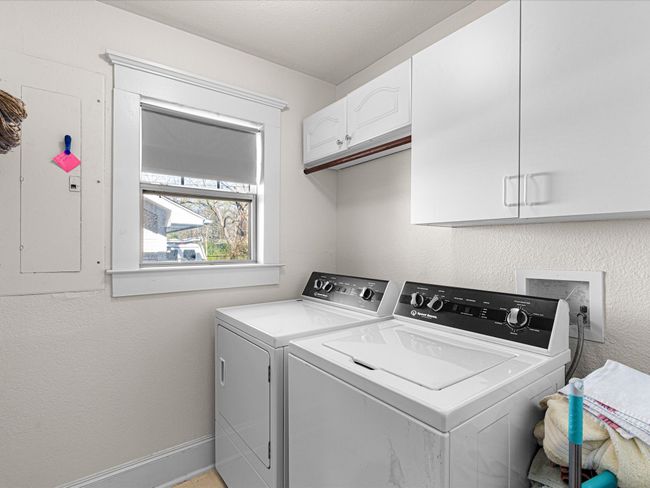 Washroom with electric panel, cabinet space, separate washer and dryer, baseboards, and a textured wall | Image 32