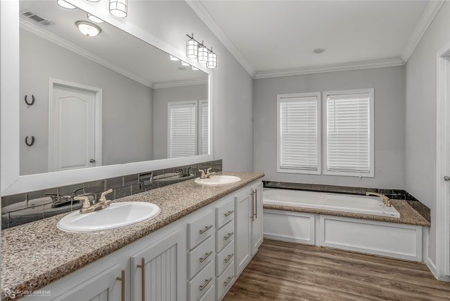 Bathroom with wood finished floors, visible vents, ornamental molding, and a sink | Image 27