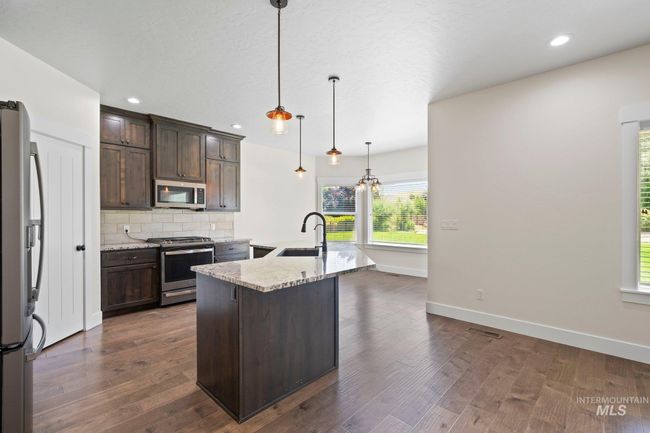 Kitchen featuring stainless steel appliances, dark brown cabinetry, tasteful backsplash, light stone countertops, and recessed lighting | Image 9