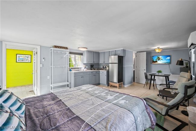 Bedroom with sink, ensuite bathroom, light tile patterned flooring, and stainless steel fridge | Image 24