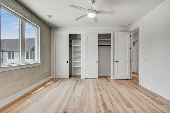 Unfurnished bedroom with baseboards, light wood-style floors, multiple closets, and a ceiling fan | Image 16
