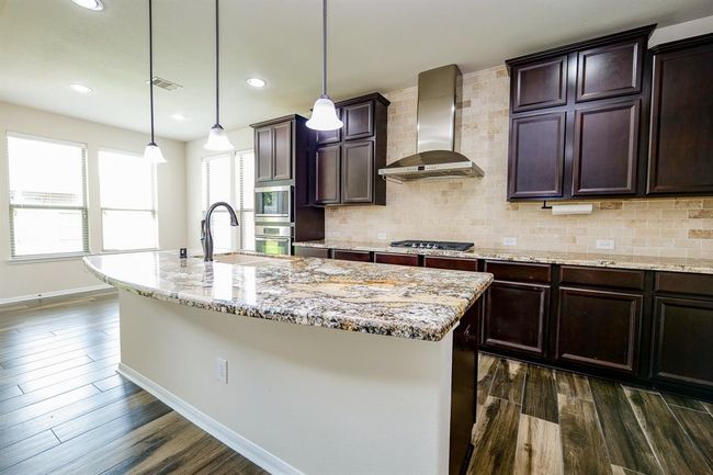 The dynamic visual appeal of dark/light contrasting tones and features in this kitchen is a winning one; with double ovens; deep chocolate colored cabinetry, up and down, and gorgeous granite counter tops, generously placed everywhere your culinary tasks take you! | Image 11