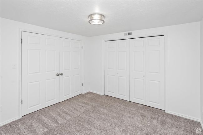 Unfurnished bedroom featuring carpet flooring, a textured ceiling, baseboards, and visible vents | Image 32