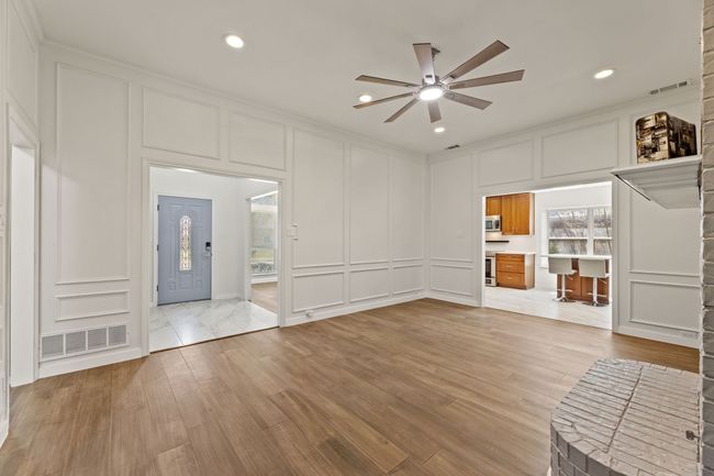 Unfurnished living room featuring light wood-type flooring, visible vents, ceiling fan, and a decorative wall | Image 16