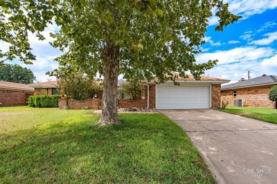 Ranch-style house with a front lawn, a garage, and central AC | Image 1