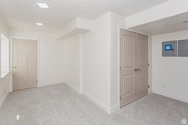 Interior space featuring a textured ceiling, electric panel, visible vents, and baseboards | Image 29