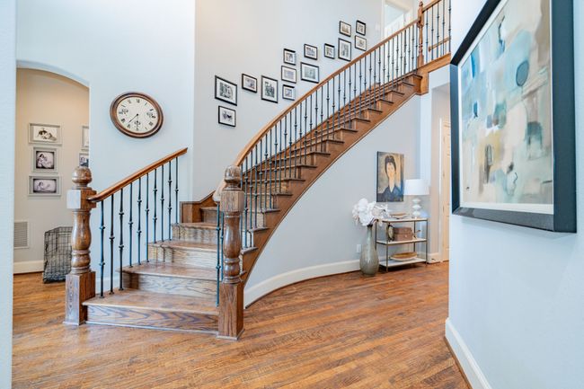 Staircase with baseboards, wood finished floors, a high ceiling, and arched walkways | Image 21