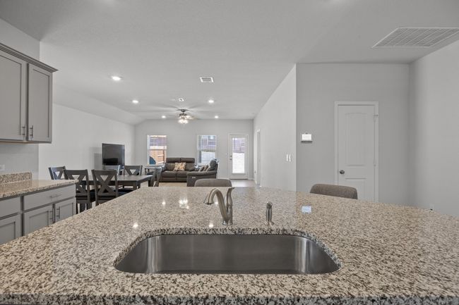 Kitchen featuring gray cabinetry, granite countertops, open floor plan, and a large sink | Image 11