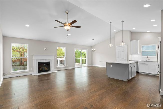 Unfurnished living room with ceiling fan, lofted ceiling, a sink, a premium fireplace, and dark wood-type flooring | Image 13