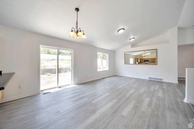 Living room with a chandelier, LVP floors, lofted ceiling | Image 8