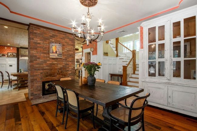 Dining room with dark wood-style floors, a chandelier, stairs, and a fireplace | Image 7