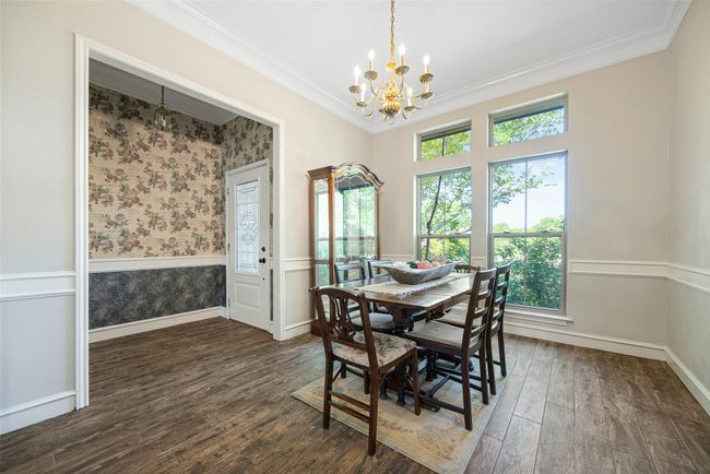 Dining space featuring baseboards, ornamental molding, a chandelier, wainscoting, and wood finished floors | Image 5